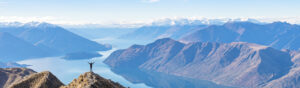 Someone standing on top of a mountain with their arms raised feeling victorious
