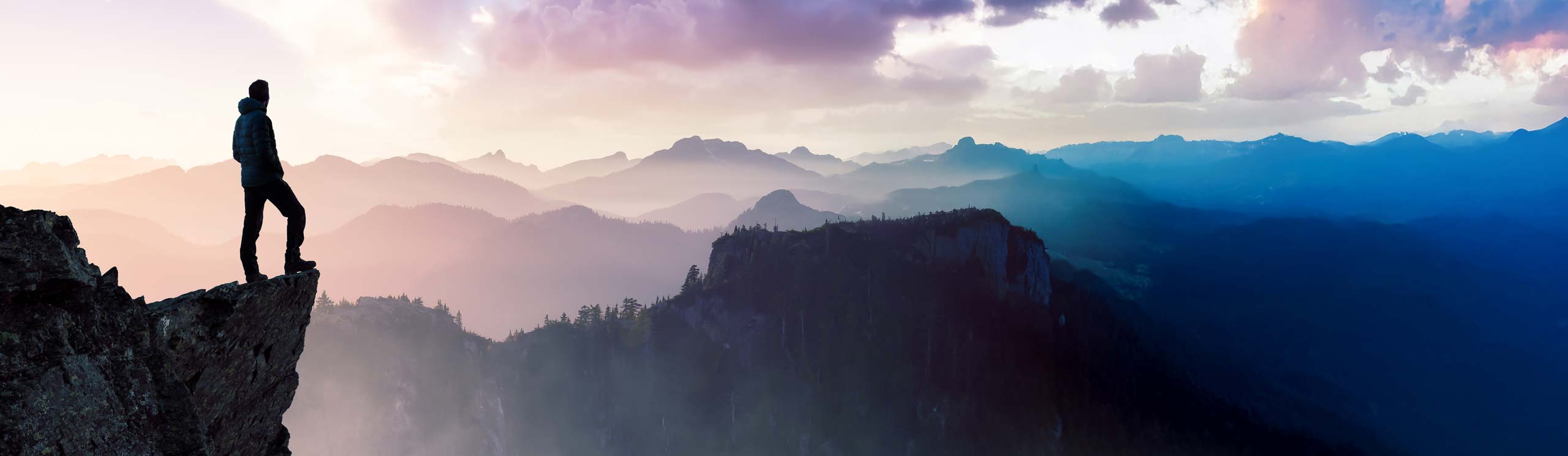 Person standing on the edge of a cliff looking out over the horizon