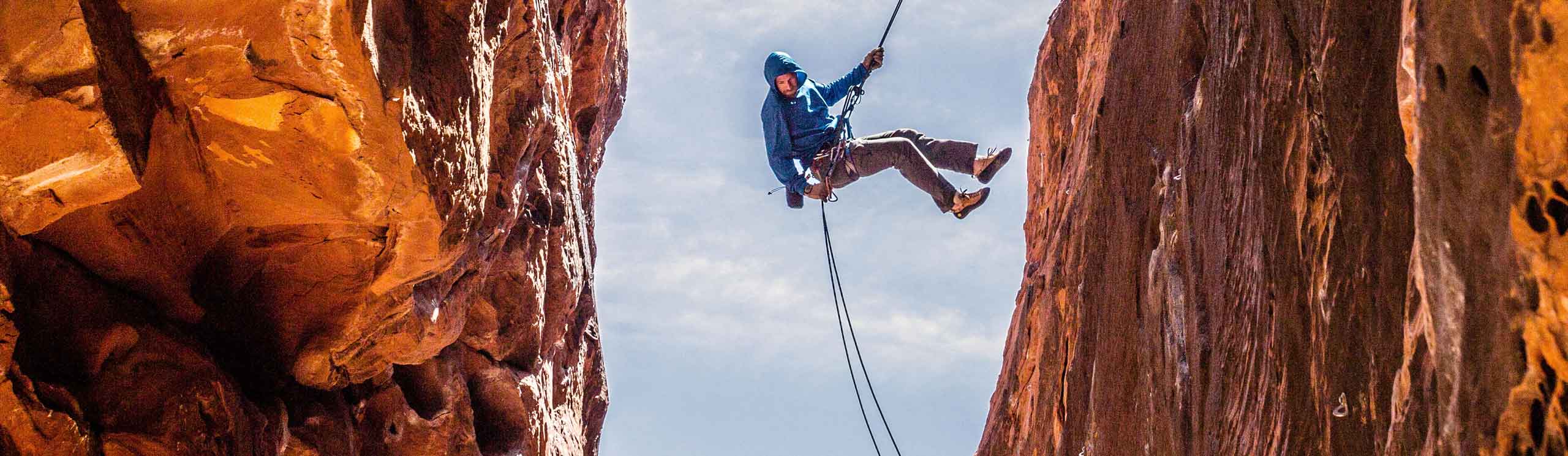 Climber handing between two cliffs from a safety rope
